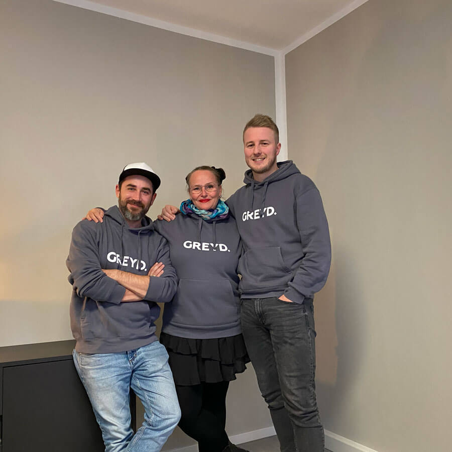 From left to right: Thomas Koschwitz, Anne-Mieke Bovelett and Jakob Trost. All three are wearing dark gray sweatshirts with a white version of the GREYD logo.